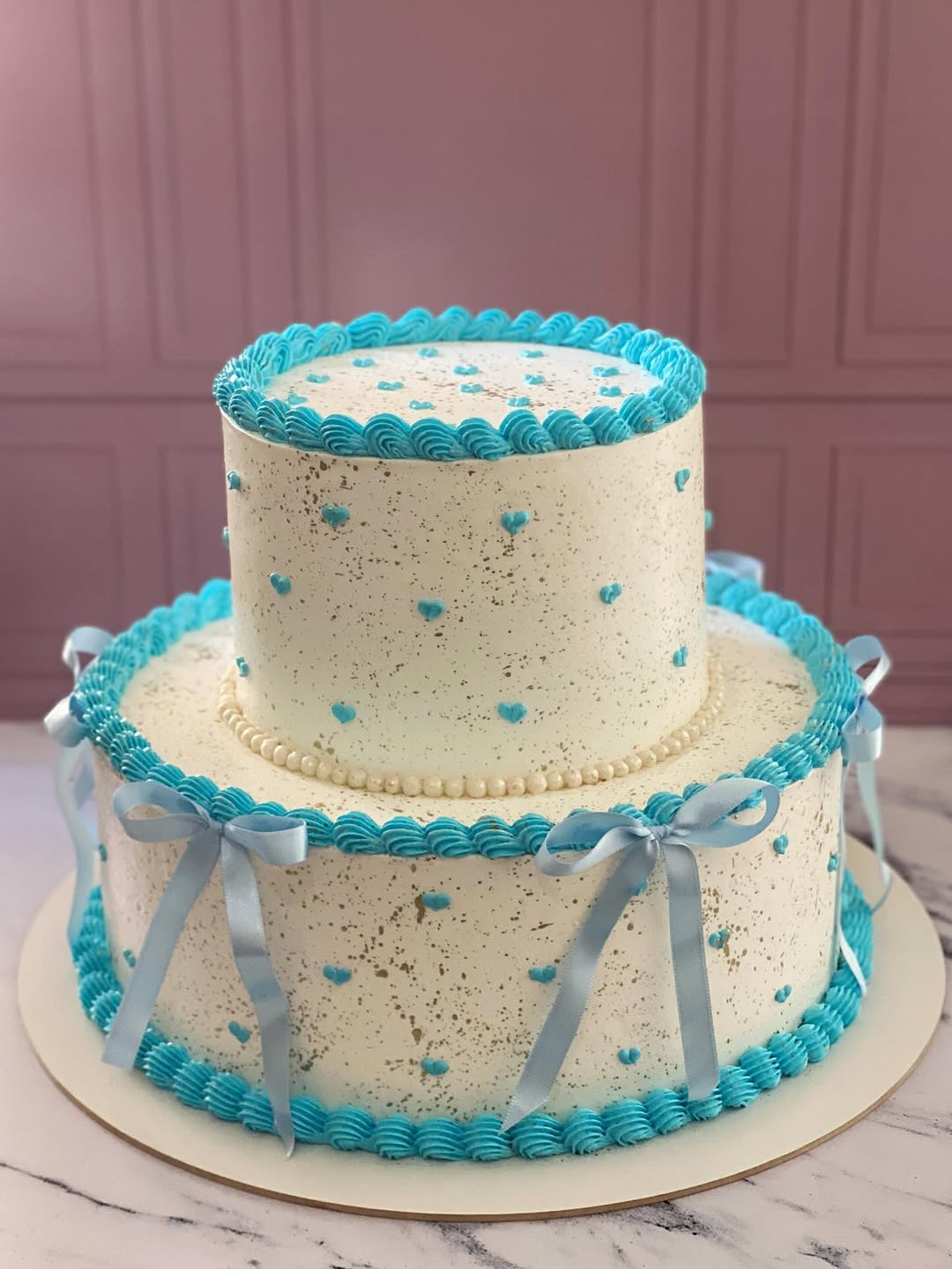 Bolo de dois andares com decoração azul e pérolas